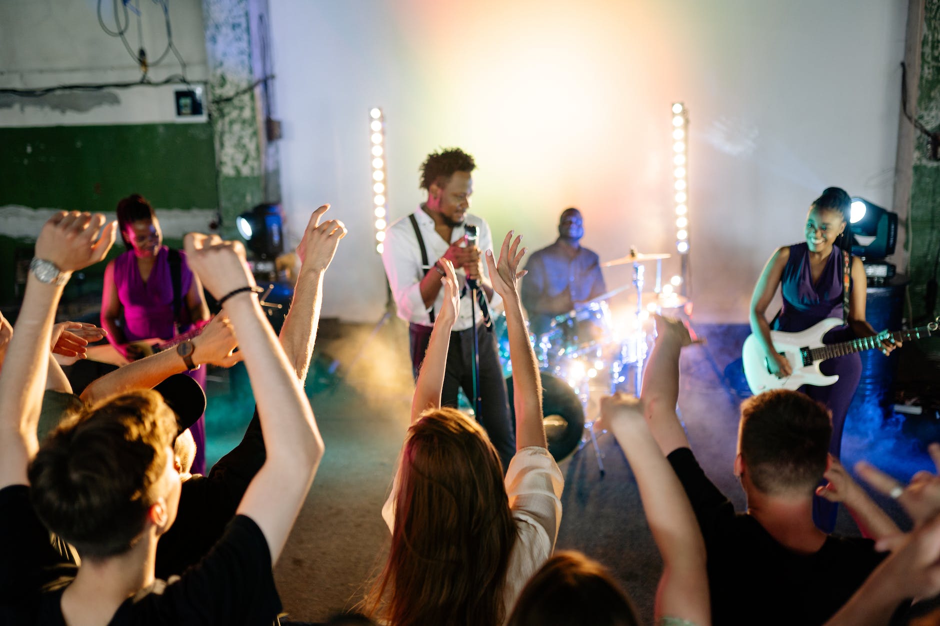 people putting hands up while dancing in front of musicians on stage